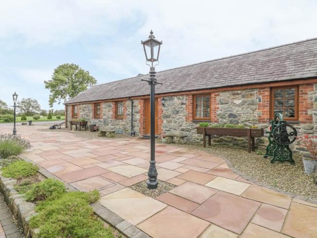 A single-storey barn conversion overlooks a patio with a Victorian streetlight in it centre.