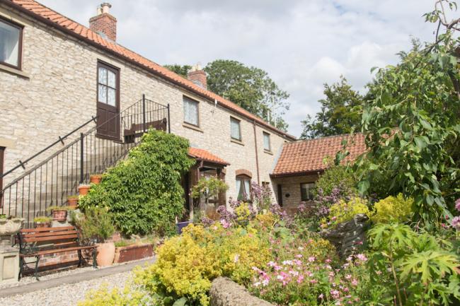 Exterior of a large barn conversion with external steps to 1st flor front door - facing a mature garden