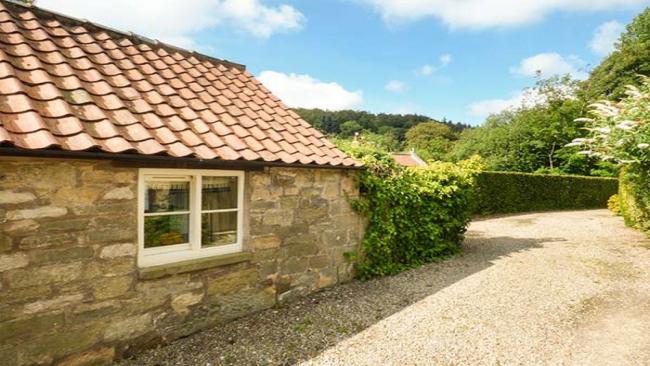 A semi-detached cottage with an enclosed front porch and a front garden behind a low stone wall