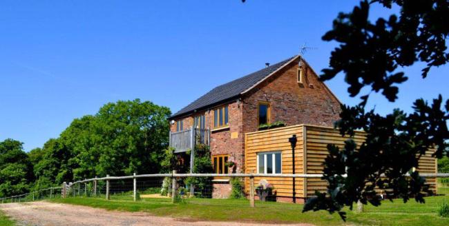 A restored barn with fenced garden and blue skies