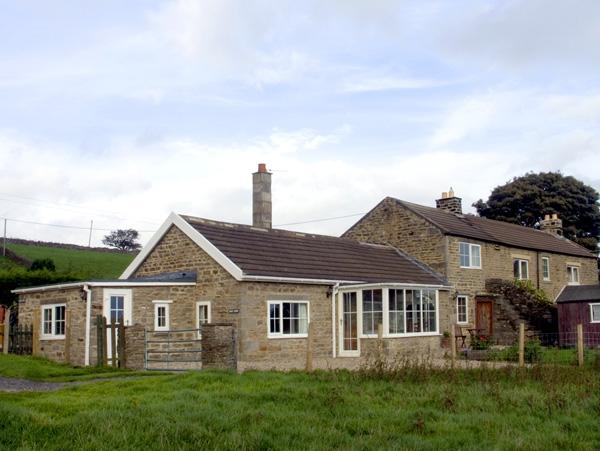 Exterior of a modern bungalow with a conservatory overlooking a grassy field.