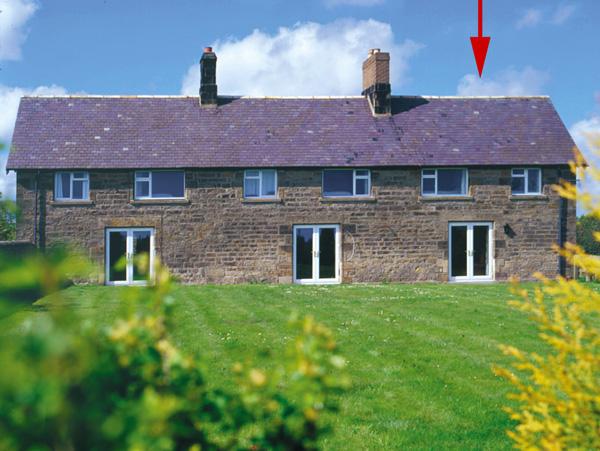 Semi-detached cottages with French windows overlook a large lawn.