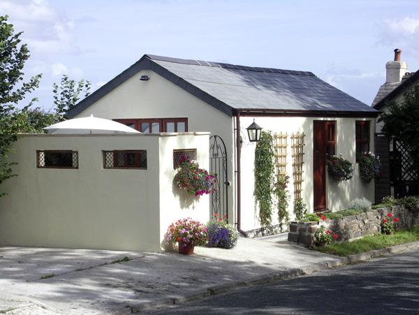 Single-storey exterior of a white-rendered bungalow with hanging flower baskets.
