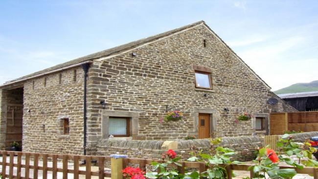 Exterior of a 2-storey, stone-built barn conversion overlooking a low-walled garden