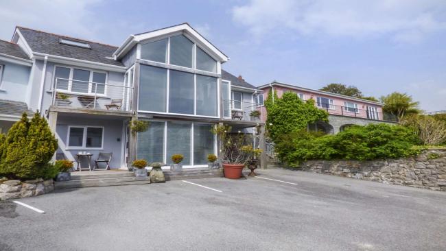 A large, contemporary 3-storey apartment building with a central gable of floor-to-ceiling windows.