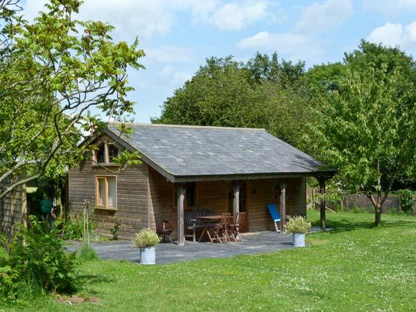 A single storey wooden barn conversion with an extended roof to create a sheltered terrace.