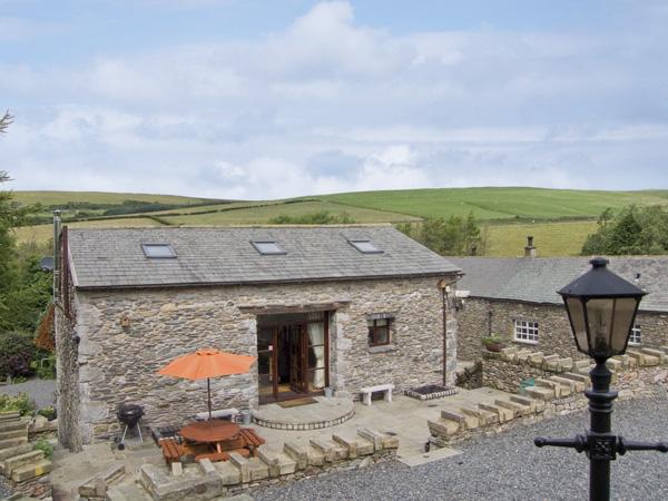 Front exterior of a stone-built barn conversion in Cumbria with a small, paved courtyard.