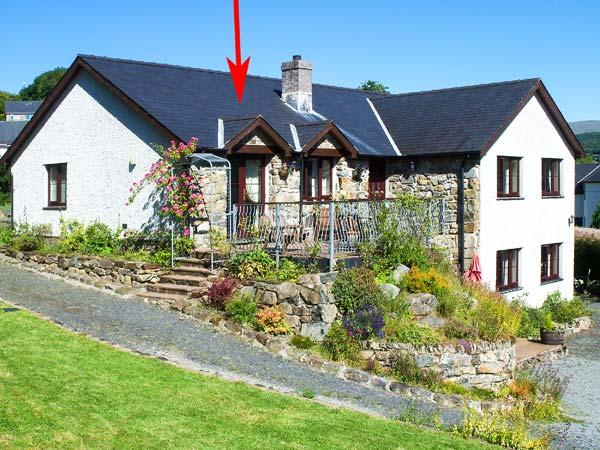 A large L-shaped Gwynedd holiday cottage house with a deck and rockery garden. garden.