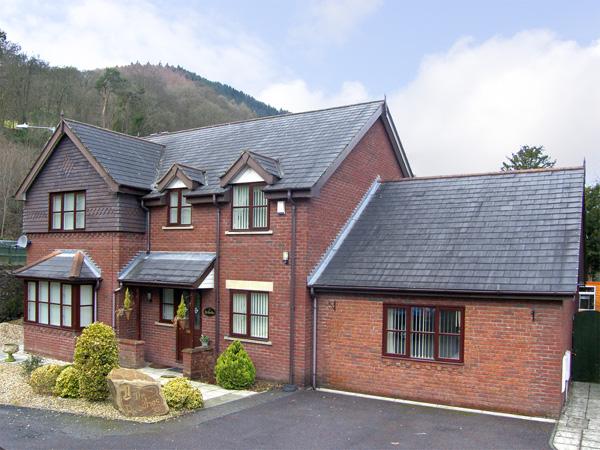 Exterior of modern a 2-storey brick house facing  a garden with off-road parking for 2-3 cars.