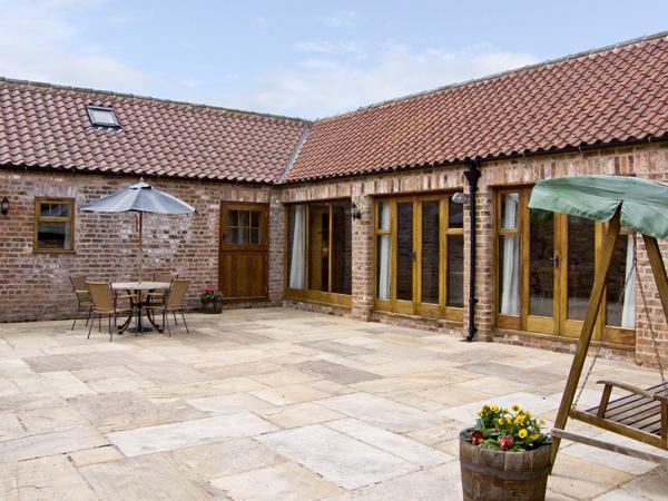 A courtyard barn conversion with a frontage comprising wall-to-ceiling French windows.