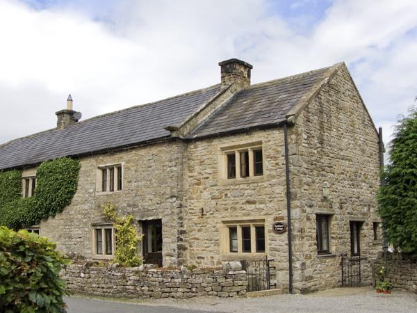 Large LEyburn holiday cottage built with local stone and surrounded by a low stone wall.
