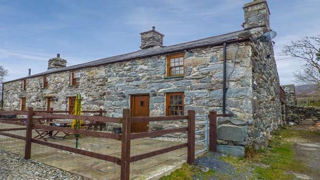 An end-terrace stone-built Gwynedd holiday cottage with a paved, secure front patio.