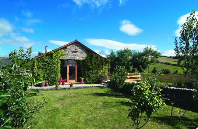 The Gable end of a single-storey barn conversion overlooks a country garden.