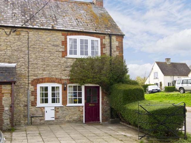 A semii-detached Dorset cottage overlooks a paved front courtyard for parking.