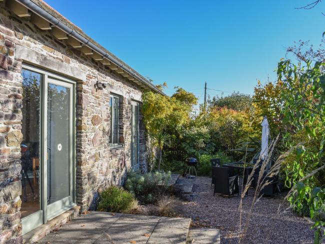 A single storey barn conversion with Frenchwindos and a mature garden of shrubs and small trees.
