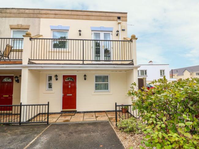 A semi-detached with a large 1st floor balcony overooks a front garden with off-road parking.