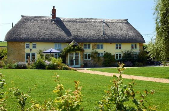 A large thatched cottage overlooking a spacious lawn near Bridport.