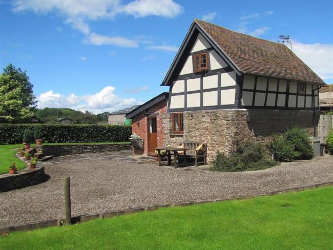 A historic black-and-white-timbered Herefordshire barn conversion with a large lawn.