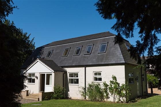 Exterior of a 2-storey coach house conversion with covered porch and garden lawn