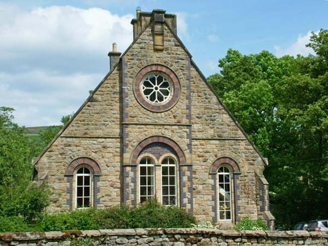 A chapel conversion with a large rose window sits behind a low stone wall.
