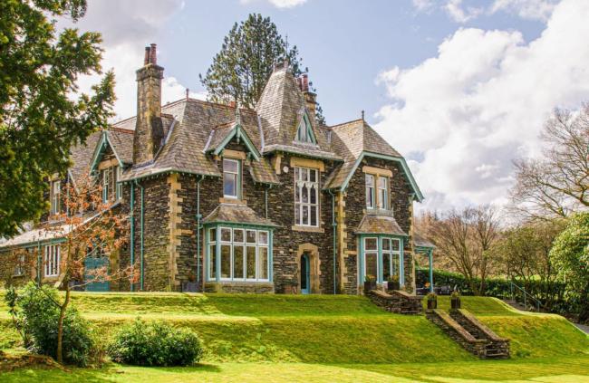 Imposing 3-storey, double-fronted stone built house with bay windows in an elevated position overlooking well-kept lawns