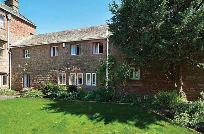 A long, 2-storey farm cottage overlooking a spacious lawn.