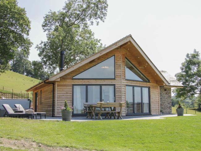 Gable end of a contemporary wooden lodge in Powys with floor-to-ceiling windows