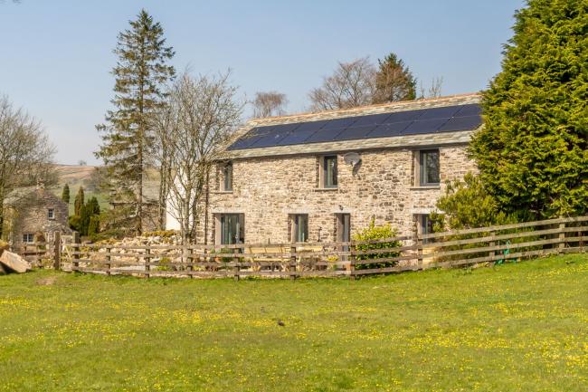 Exterior of a stone-built barn conversion overlooking a field.