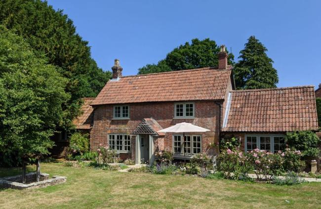 A stone-built Dorset cottage overlooks a lawn and rose beds.
