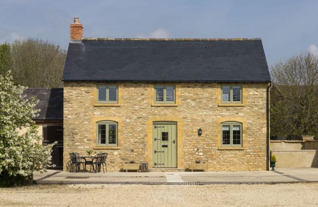 Exterior of a double-fronted Cotwolds honey-stone cottage