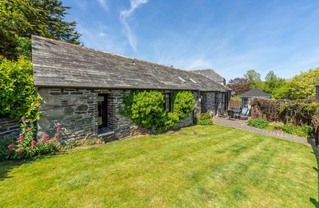 A single-storey stone barn conversion in Polzeath sits alongside a large lawn.